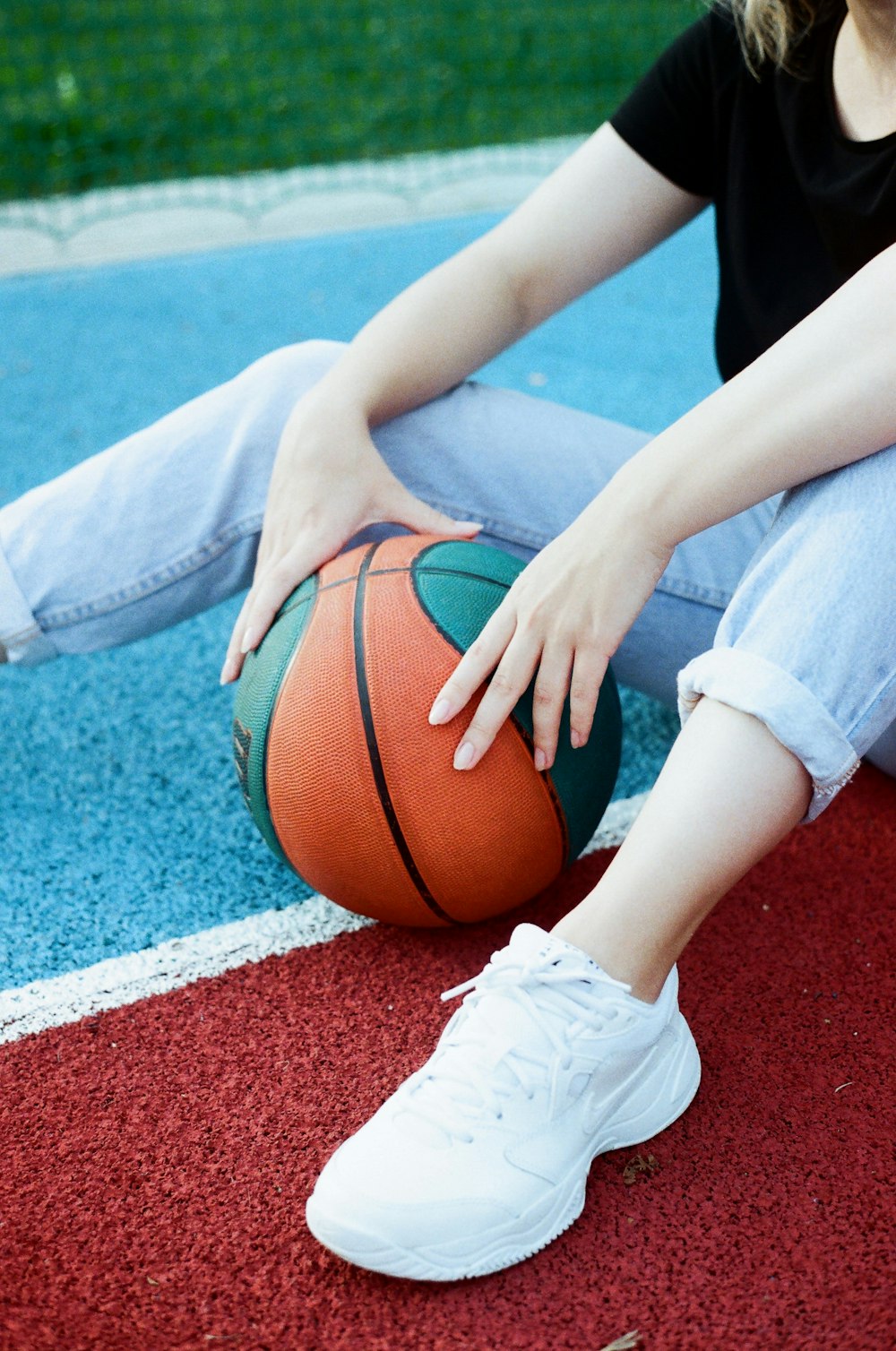 a woman sitting on the ground with a basketball