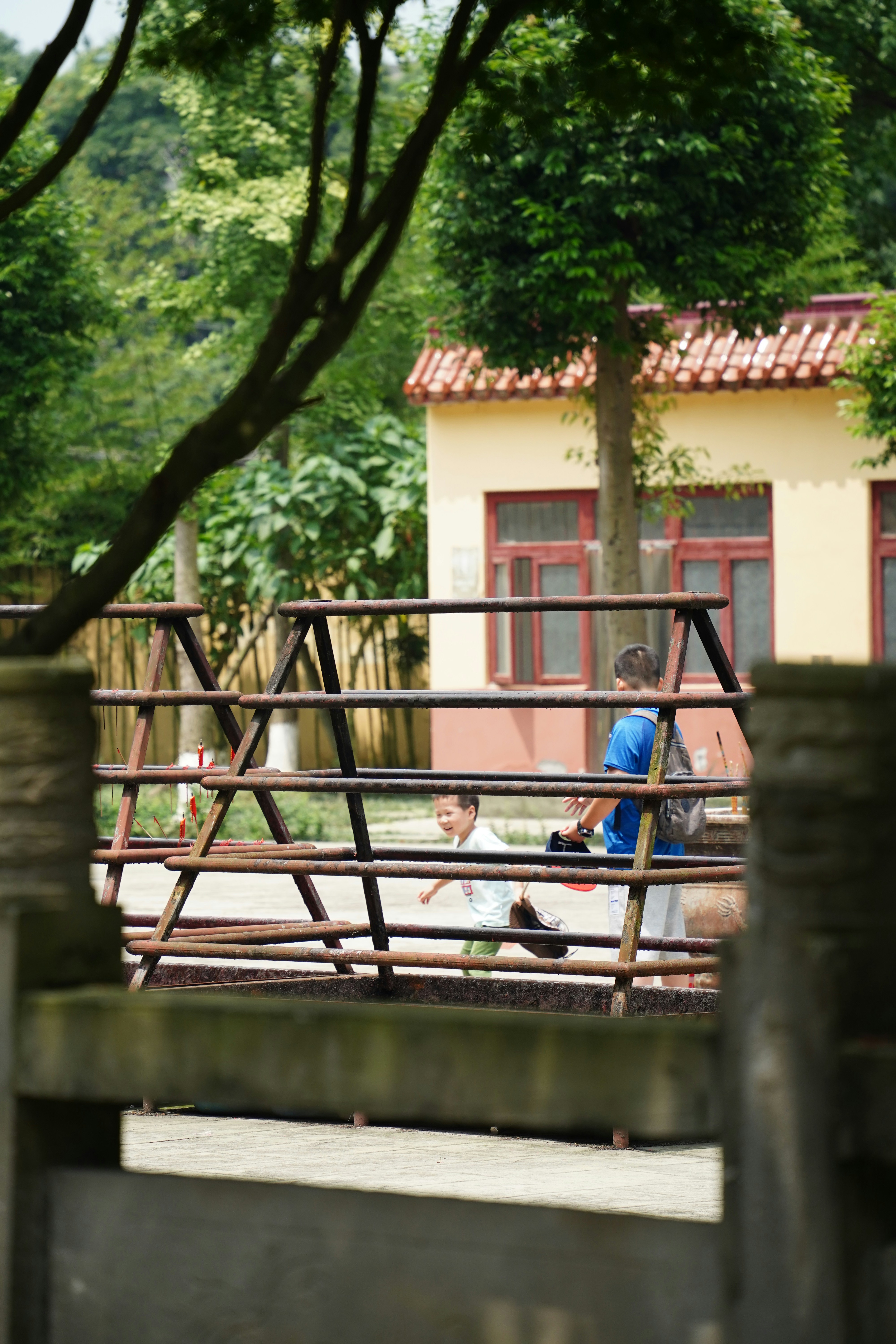 a couple of kids sitting on a wooden bench in front of a house