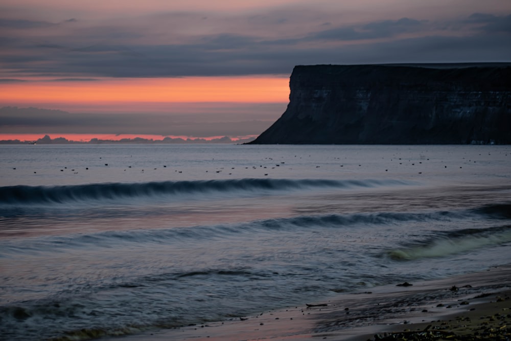 a beach with waves and a cliff