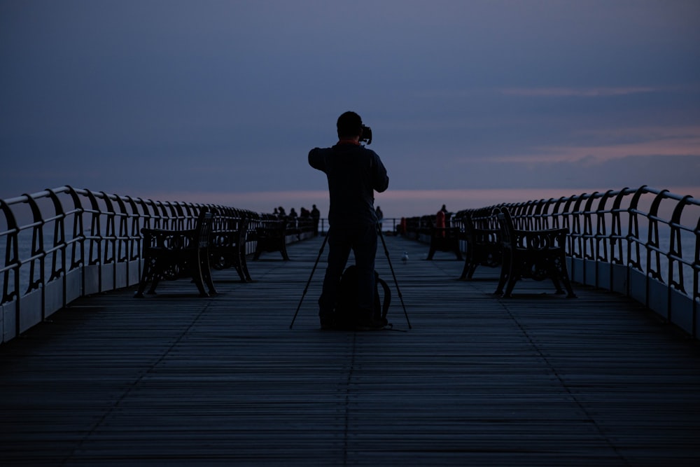 eine Person mit einer Kamera auf einem Pier