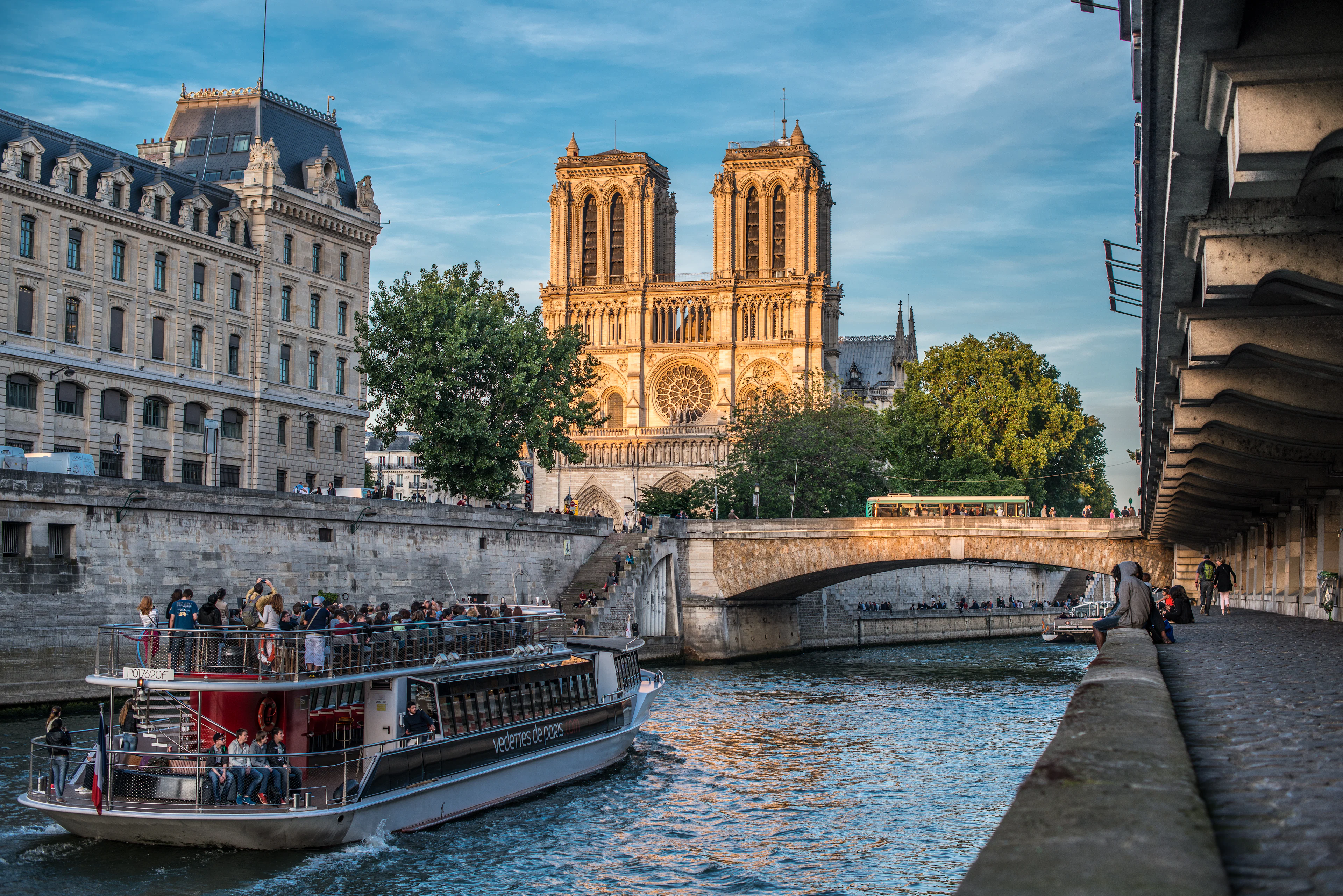 A sightseeing boat on the Seine below Notre-Dame Cathedral in warm golden light