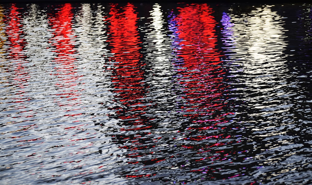 a body of water with red and orange lights reflecting on it