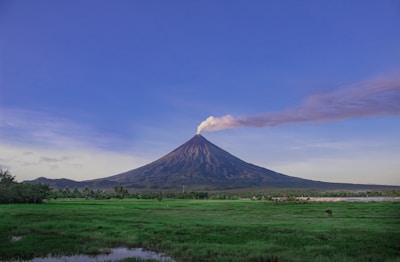 A breathtaking view of a volcano surrounded by lush greenery under a clear blue sky.