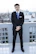 Professional photo of a young businessman in formal attire standing by Dubai's skyline.