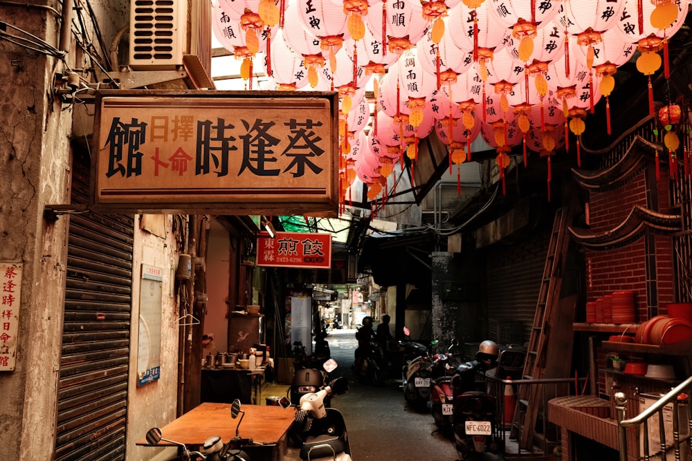 a street with a row of motorcycles and lanterns from the ceiling