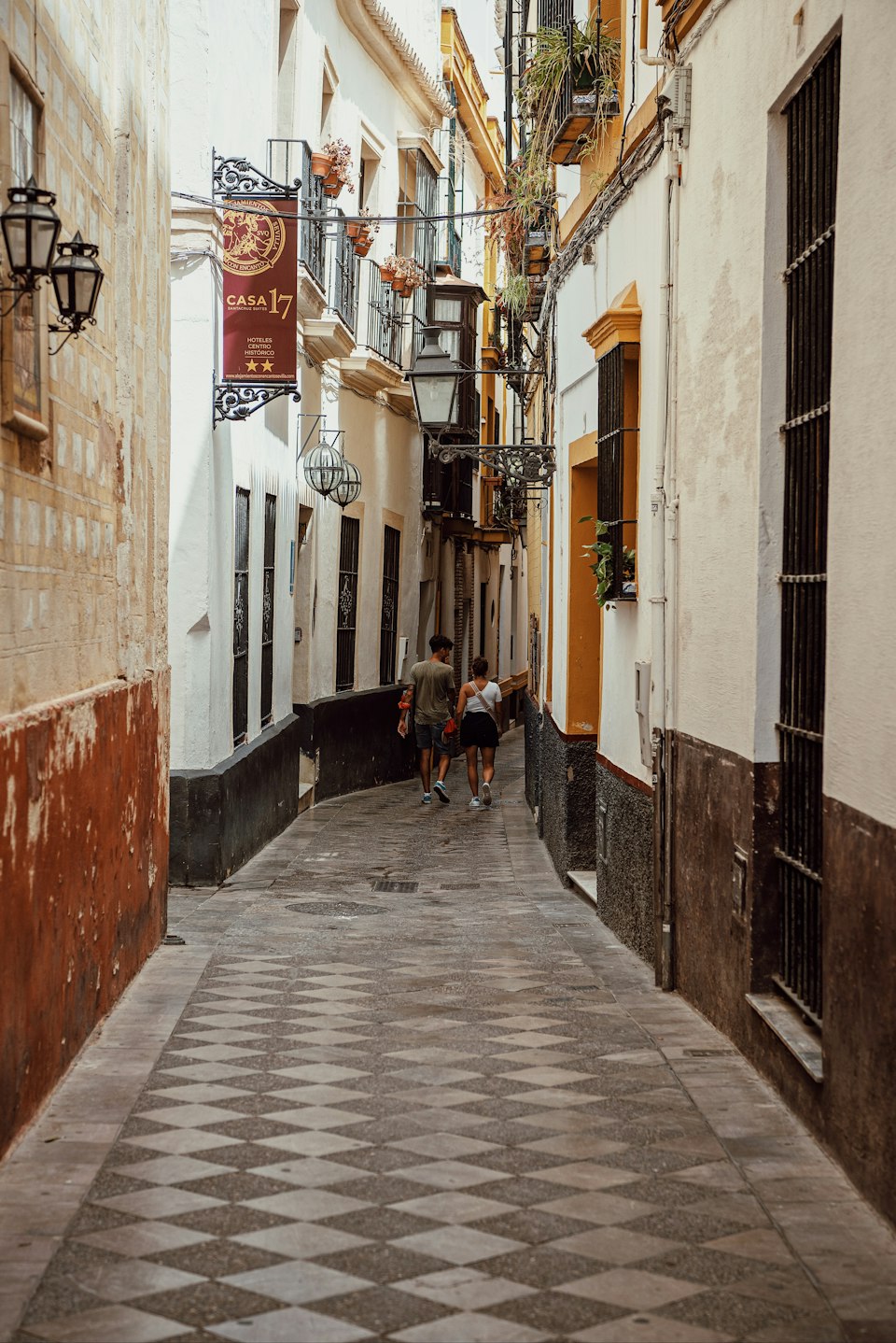 People walking through a narrow whitewashed lane in Seville's Santa Cruz quarter