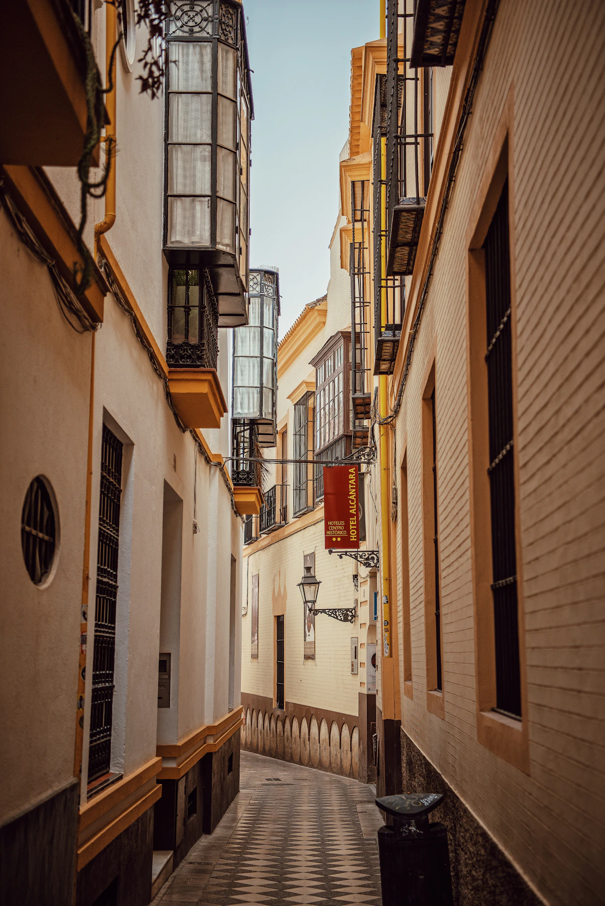 A quiet ochre and white lane with traditional glass balconies in Seville