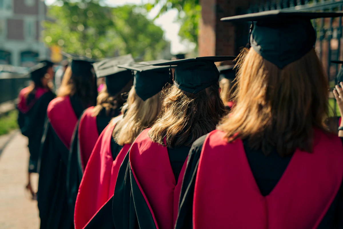 Un groupe de diplômés en toge lève sa coiffe universitaire