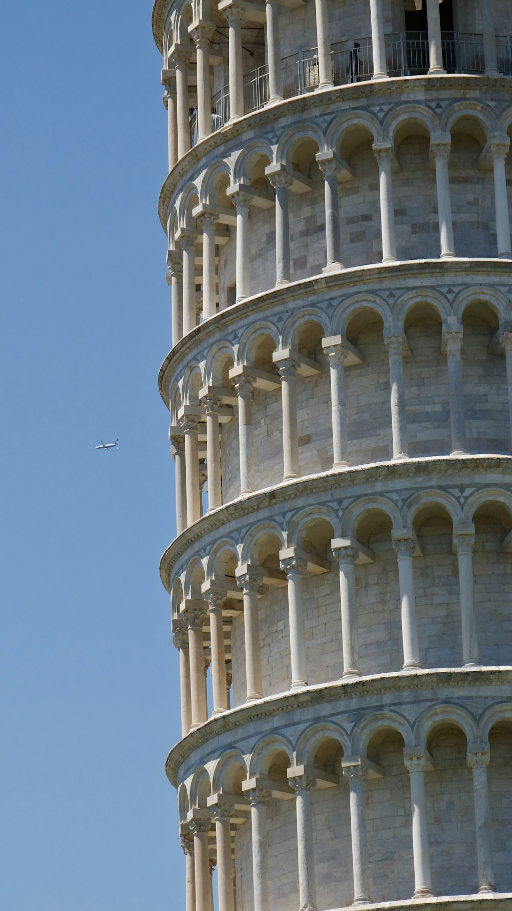 a large white building with columns with Leaning Tower of Pisa in the background