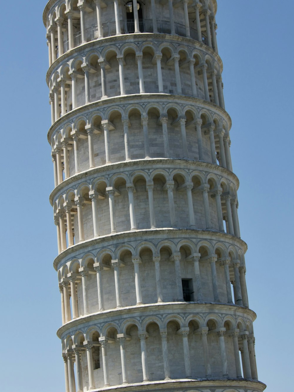 a tall white tower with Leaning Tower of Pisa in the background