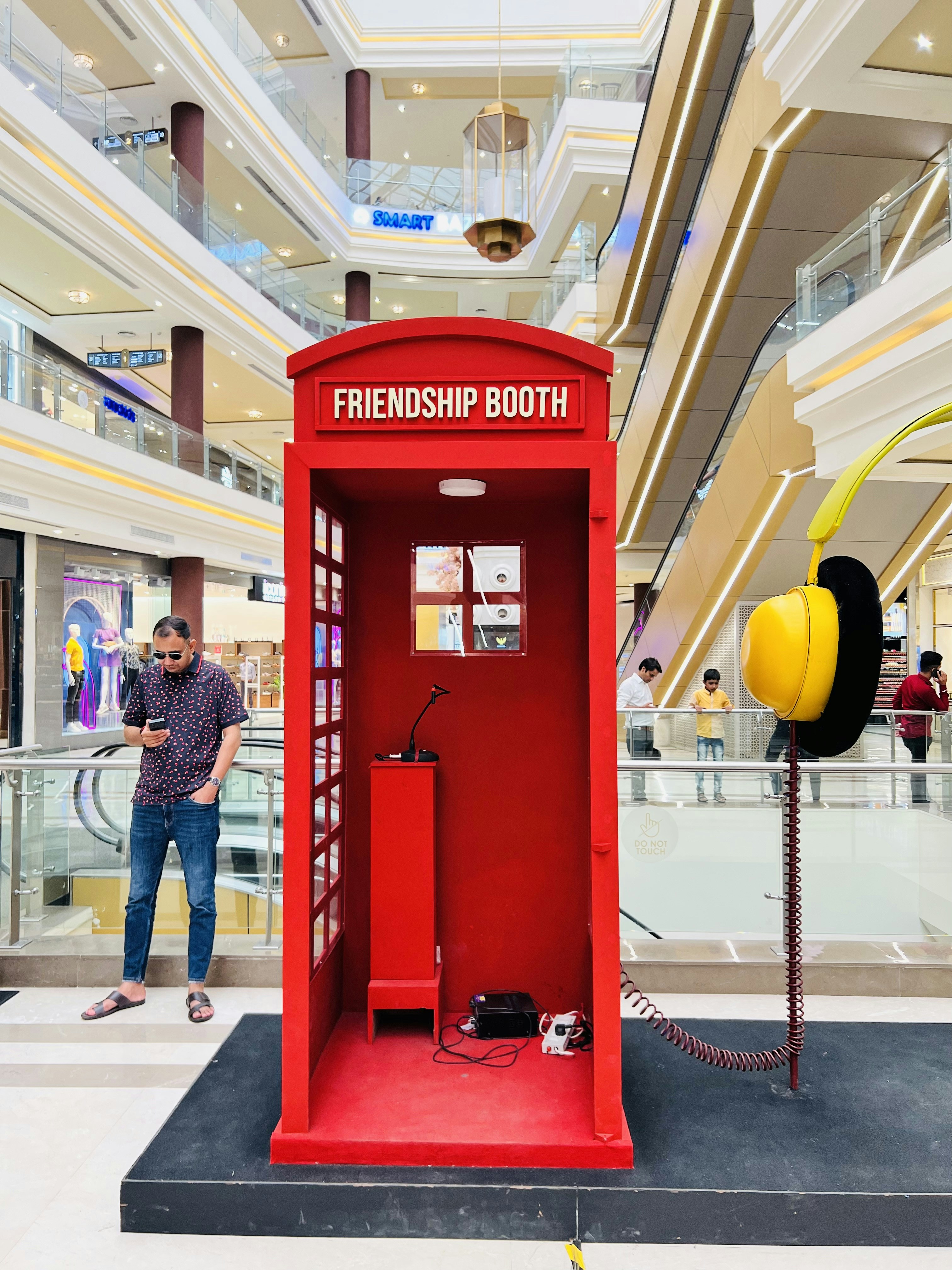 A person standing next to a red booth in a mall photo – Free Uttar ...