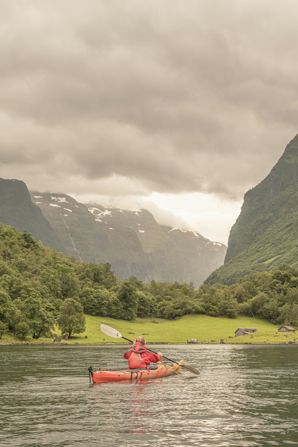 uma pessoa em uma canoa em um rio com montanhas no fundo