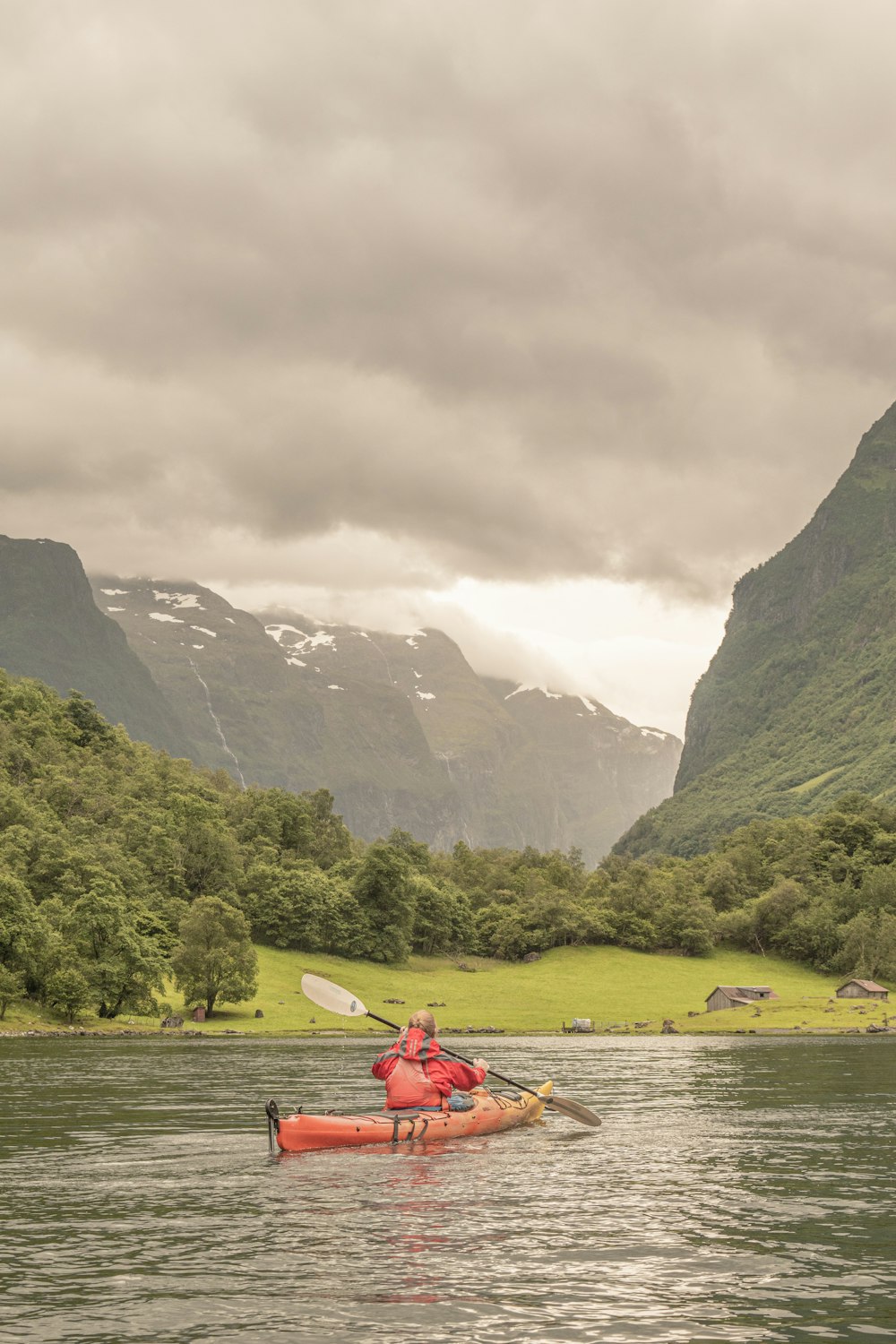 a person in a canoe on a river with mountains in the background