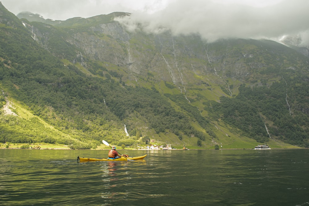 a person in a canoe in a lake with mountains in the background