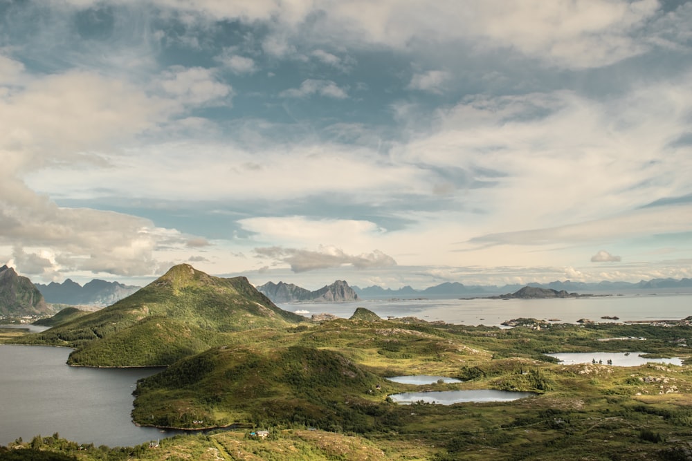 a grassy area with water and mountains in the background