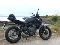 A sleek motorcycle parked on a scenic coastal road at sunset.