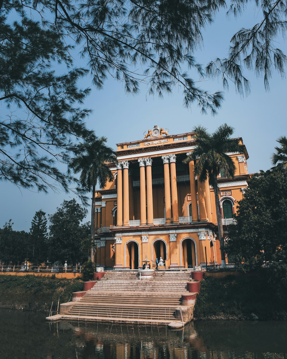 a building with columns and a body of water in front of it