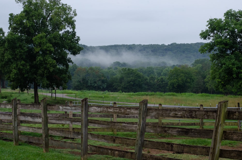 a fenced in field with trees in the background