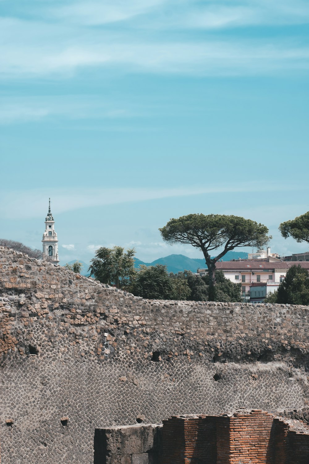 a stone wall with a tower and a building in the background