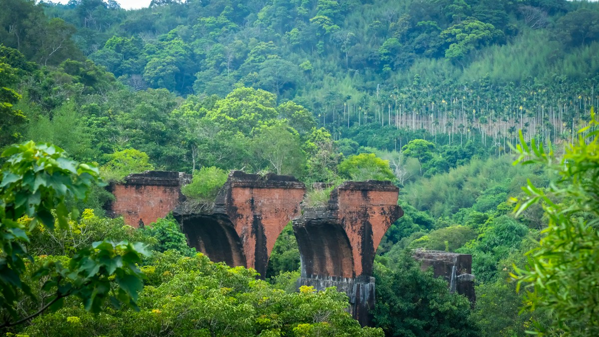 The red-brick piers of Longteng Bridge in Sanyi, Miaoli, surrounded by green forest