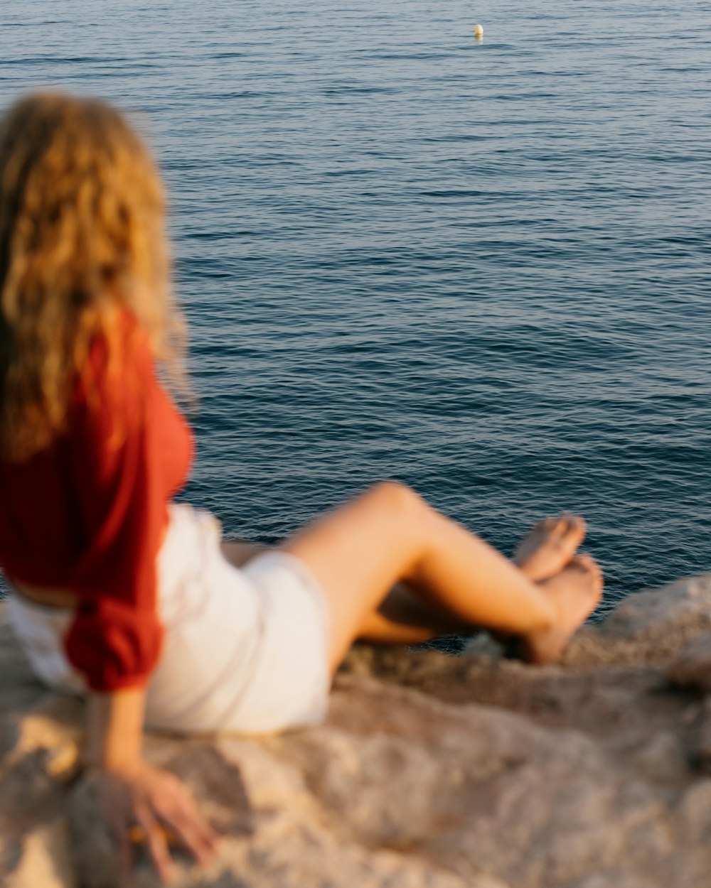 a person sitting on a rock by the water