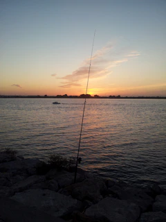 A serene mountain lake at sunset, a fishing rod leaning against a boat