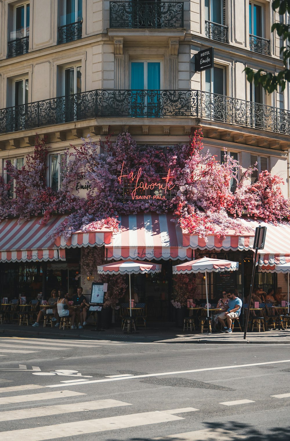 a building with a pink awning and a street with people sitting at tables