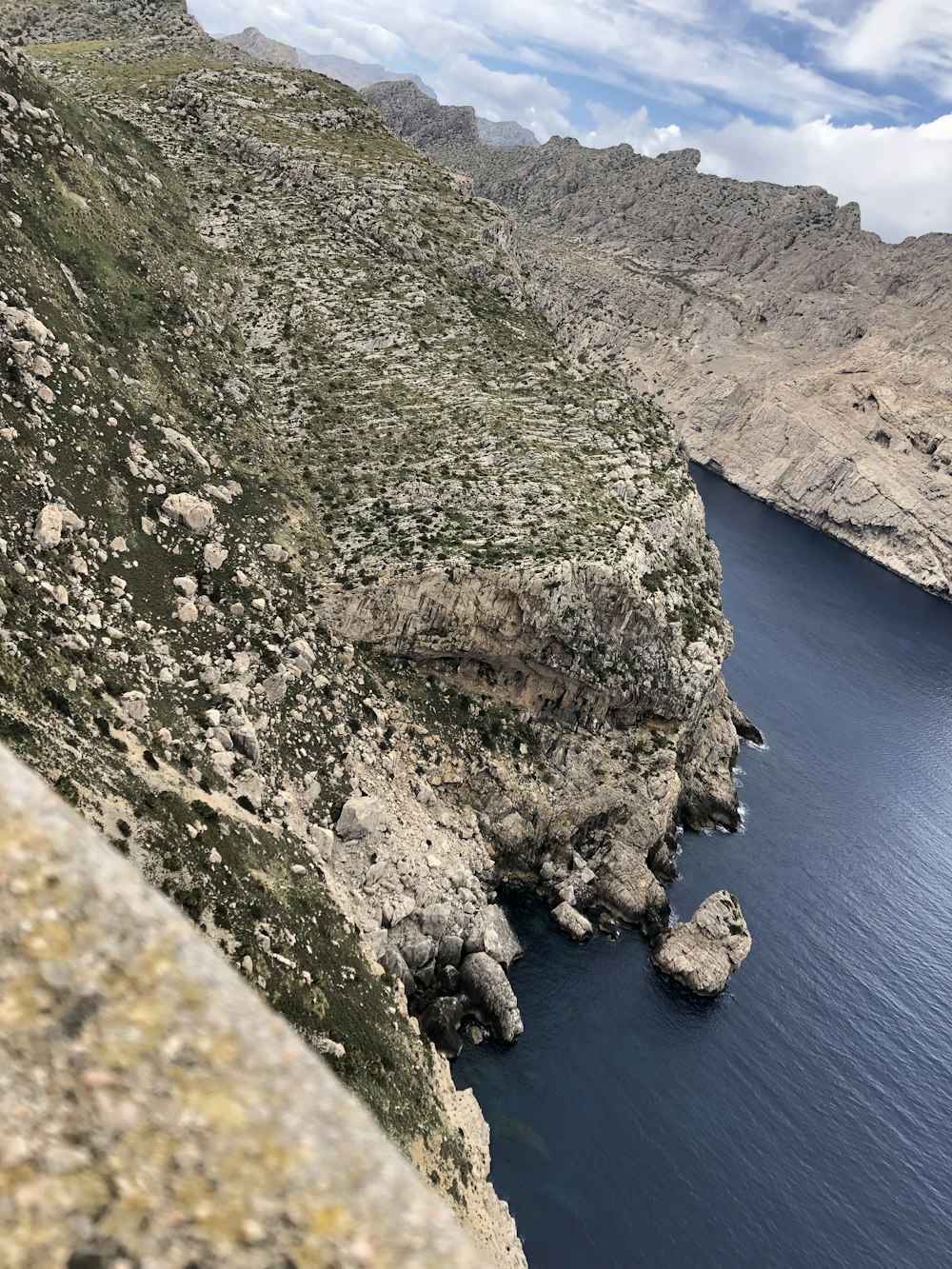 a rocky cliff next to a body of water