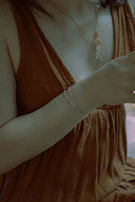 Model wearing a subtle amber pendant necklace paired with matching earrings in a warm, softly lit setting.