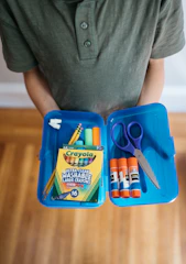 a person sits at a table with a box of scissors and a bag