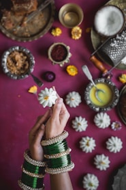 a hand holding a gold and silver bracelet with a flower design