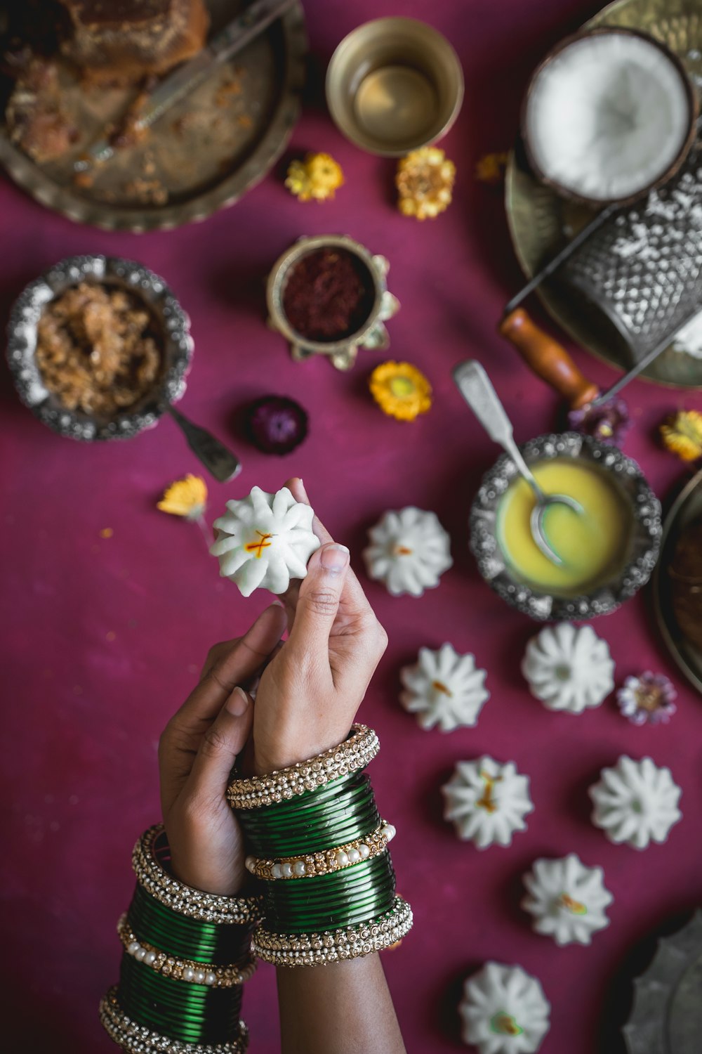 a hand holding a gold and silver bracelet with a flower design