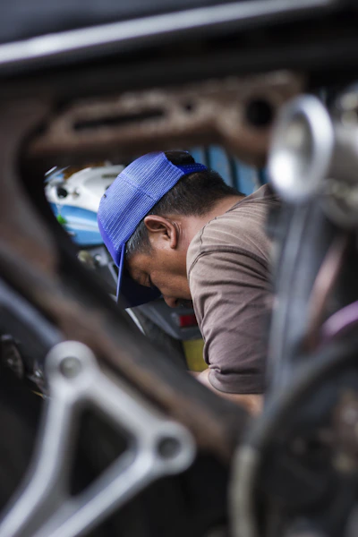 Man wearing a blue cap working on a vehicle.