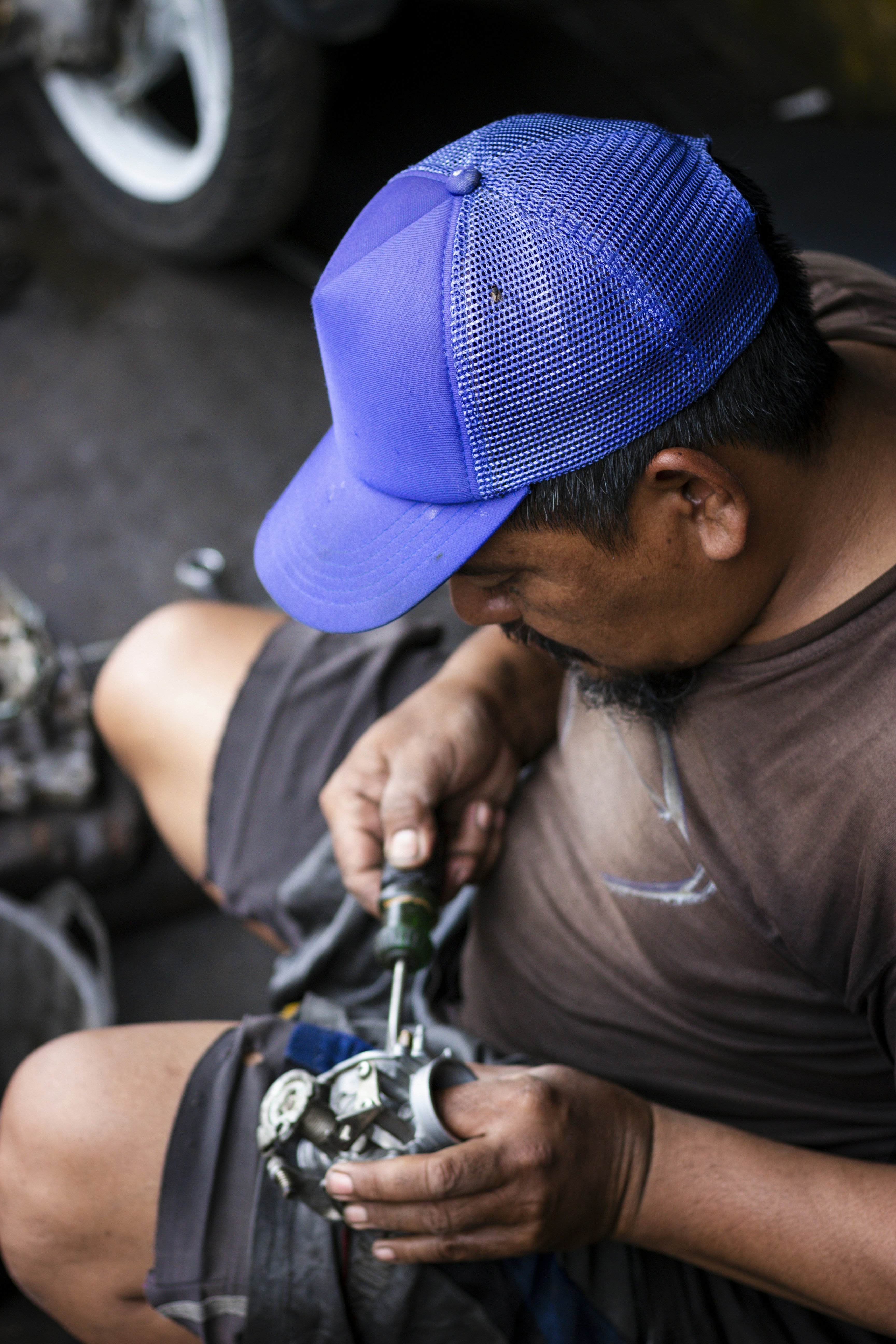 Mécanicien travaillant sur un carburateur avec un tournevis.