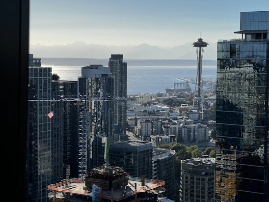 A group of engineers collaborating over blueprints with the Seattle skyline in the background.