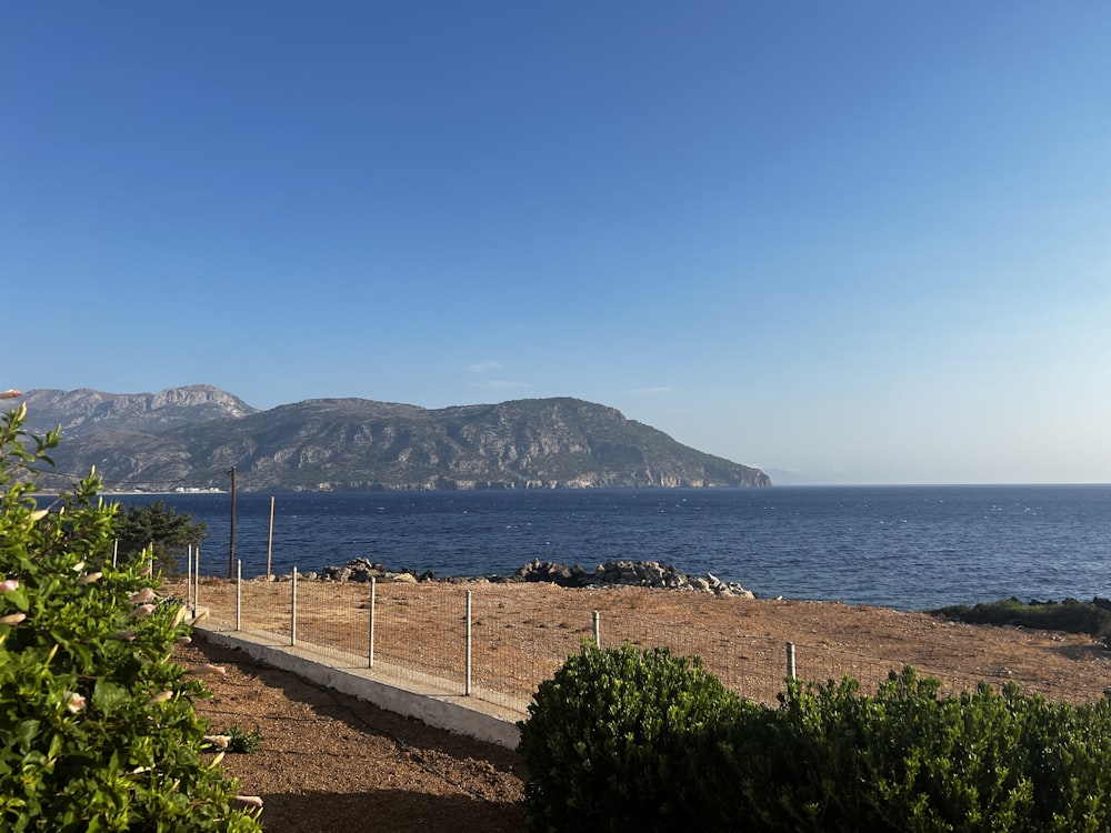 a beach with a fence and a body of water in the background