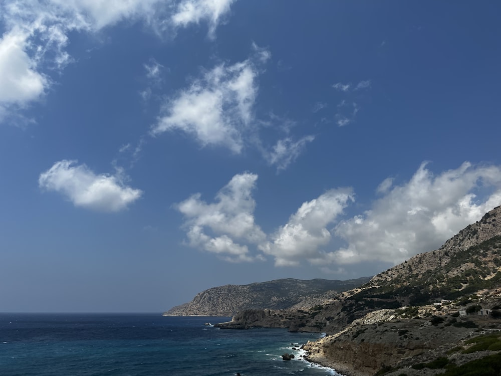 a body of water with hills and a blue sky