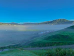 A serene Andean landscape with morning mist over green valleys and ancient trees.