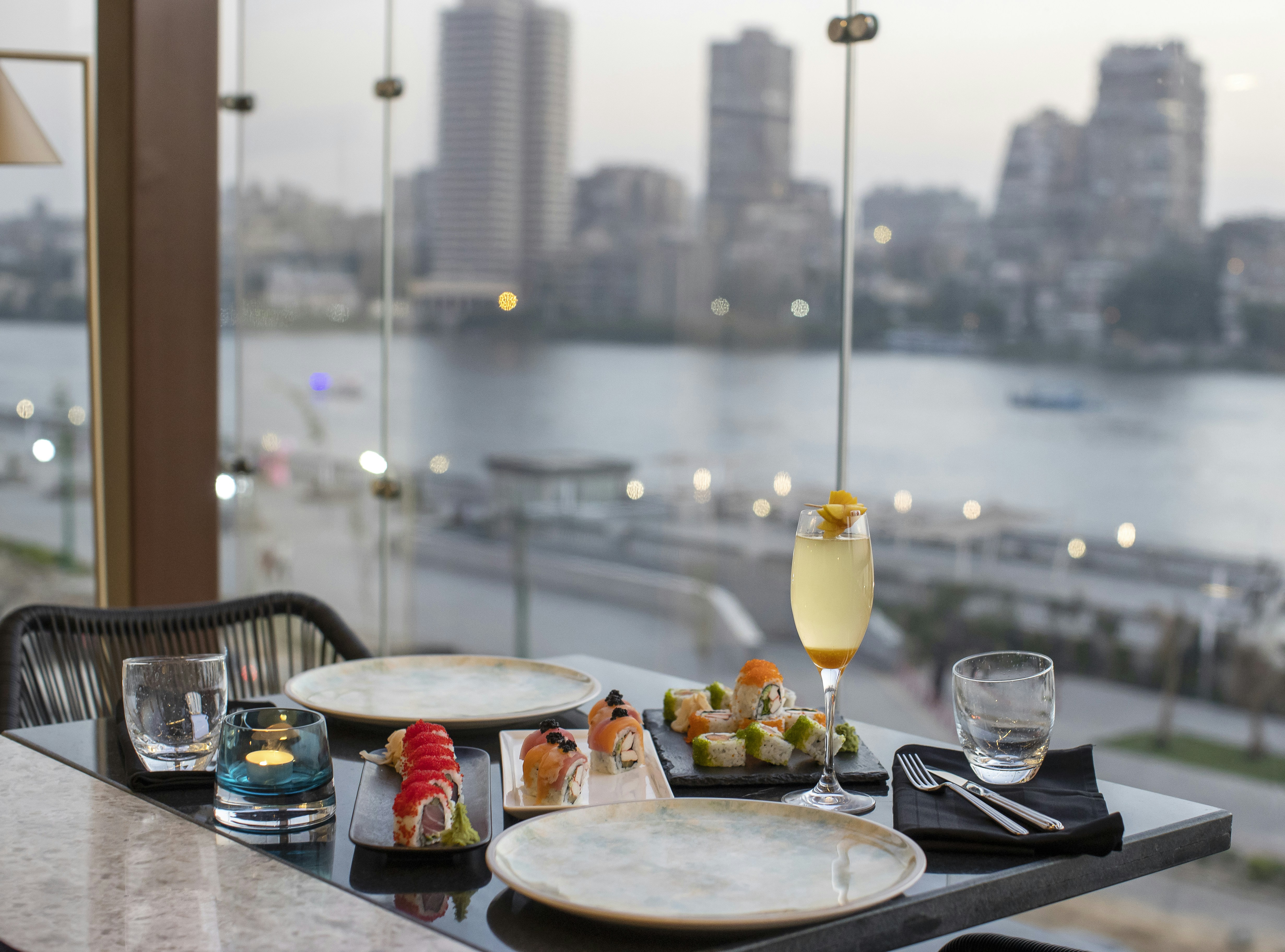 a table with plates and glasses on it with a view of a city