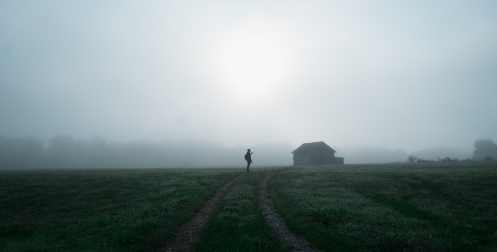 a person walking on a dirt path in a foggy field