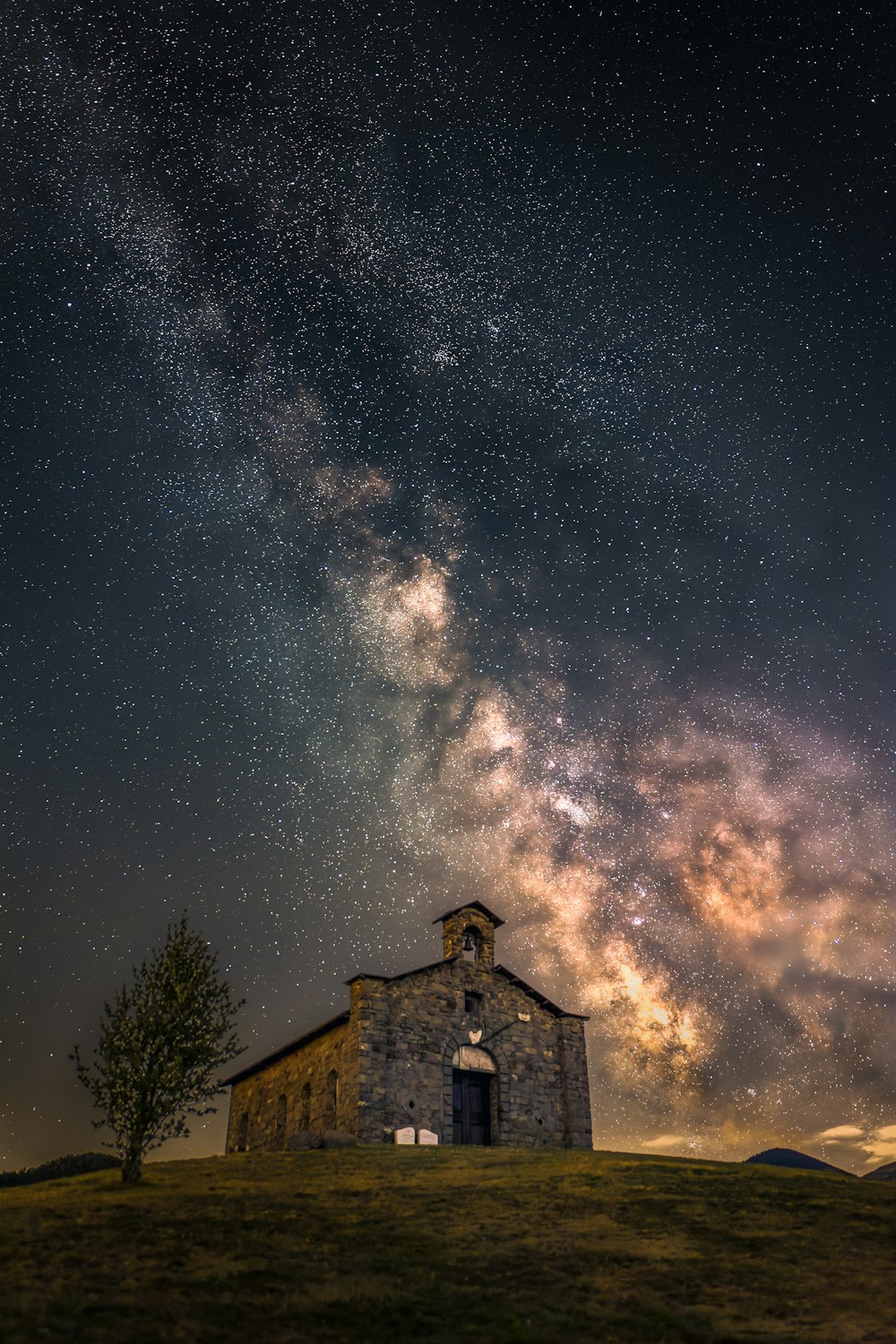 a building with a tree in front of it and stars in the sky