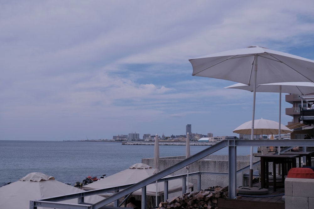 a deck with umbrellas and a body of water in the background