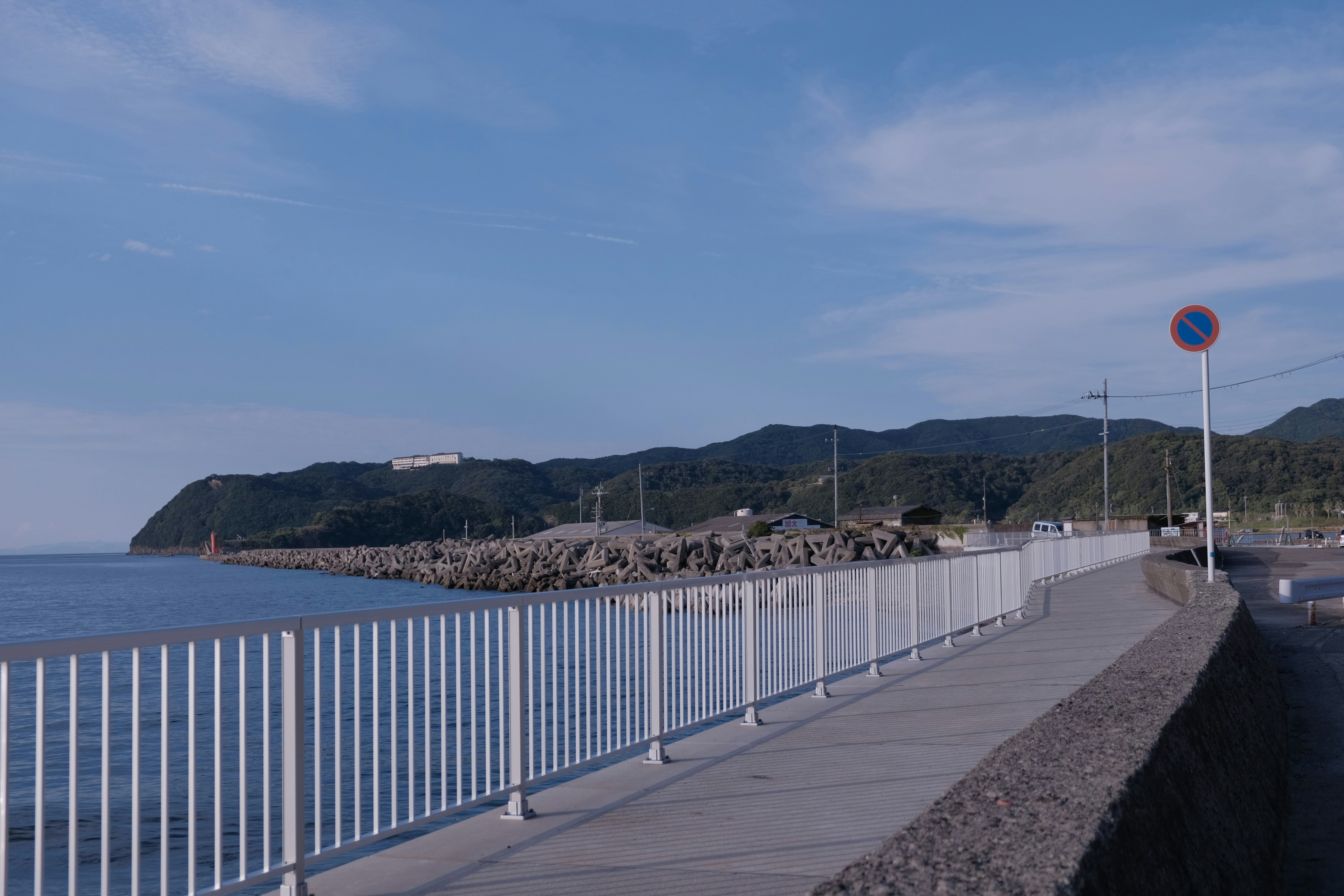 A white railing with a body of water and a hill in the background photo ...
