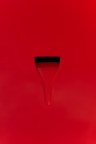A minimalist design with a bright red surface featuring a subtle groove or indentation. The indentation appears dark, creating a simple yet striking contrast against the red background.