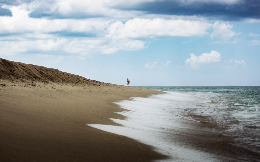 a person walking on a beach, A woman walks up the beach after a swim in the ocean.