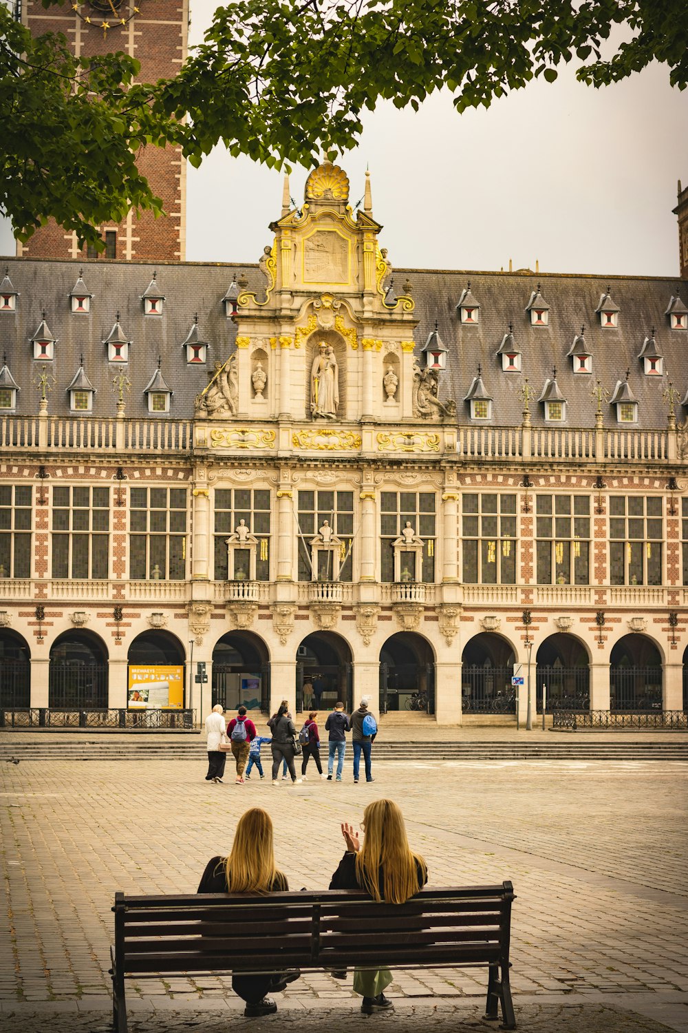 a couple of women sitting on a bench in front of a building