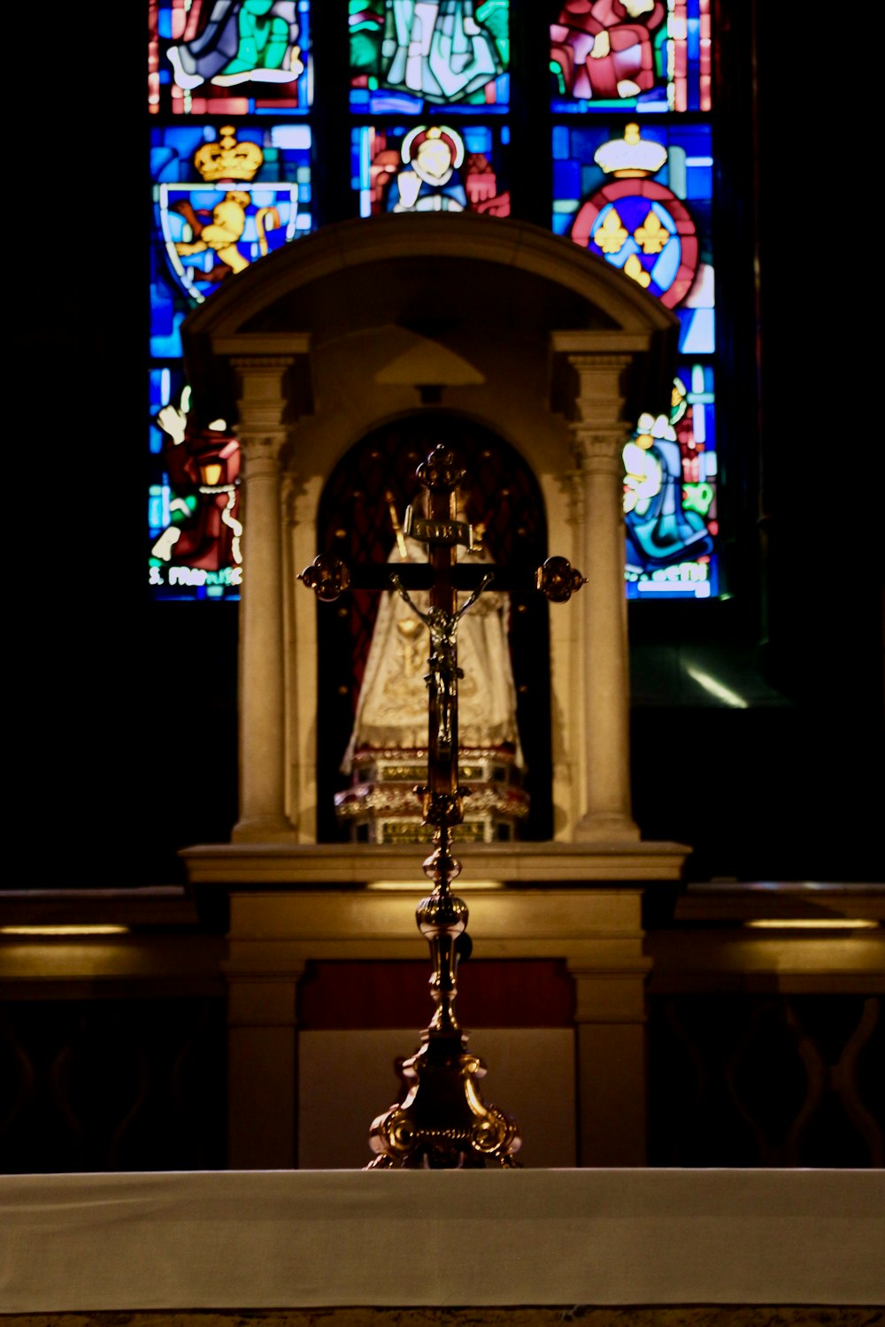 a statue in front of a stained glass window