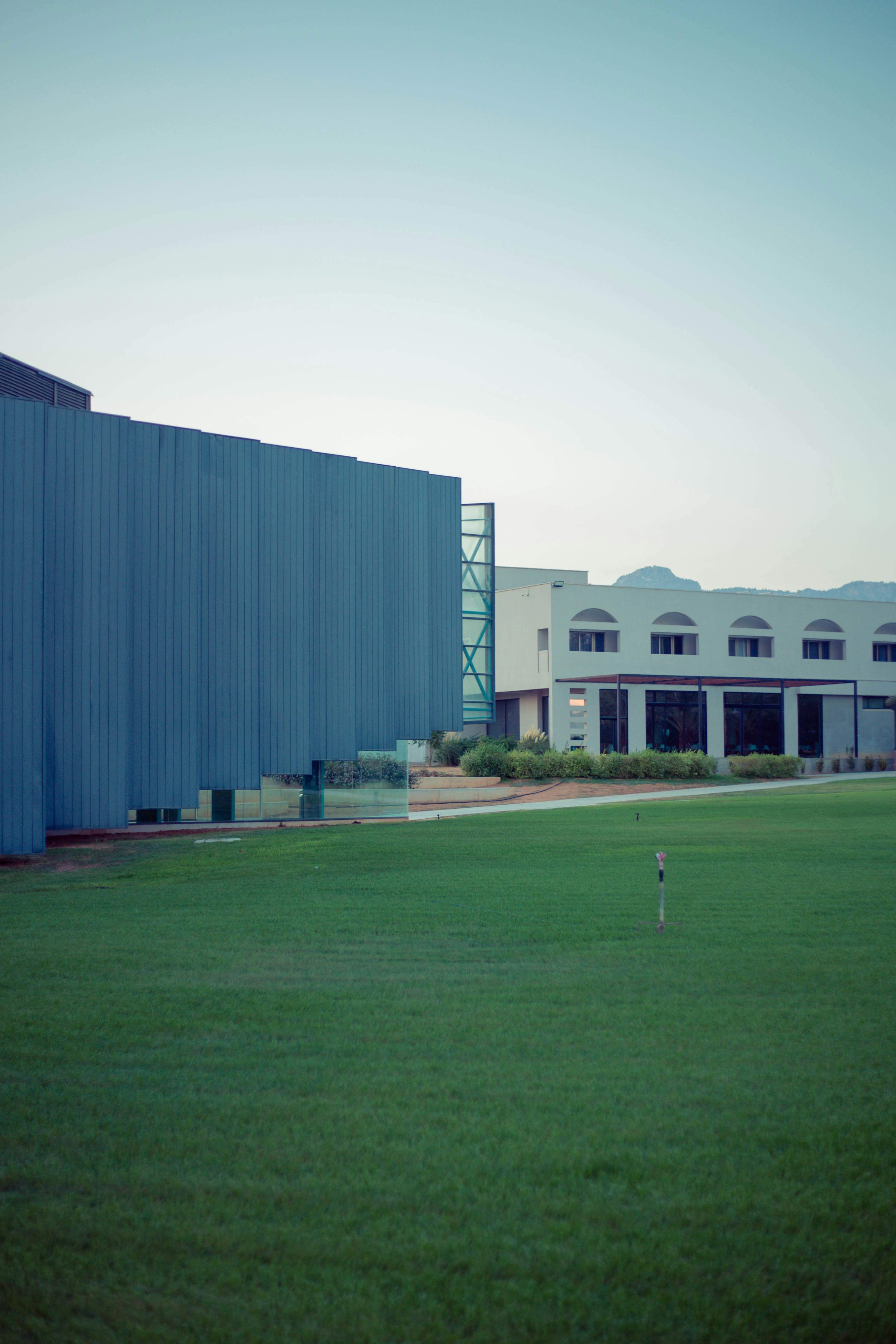 Modern buildings overlook a manicured lawn with distant hills.