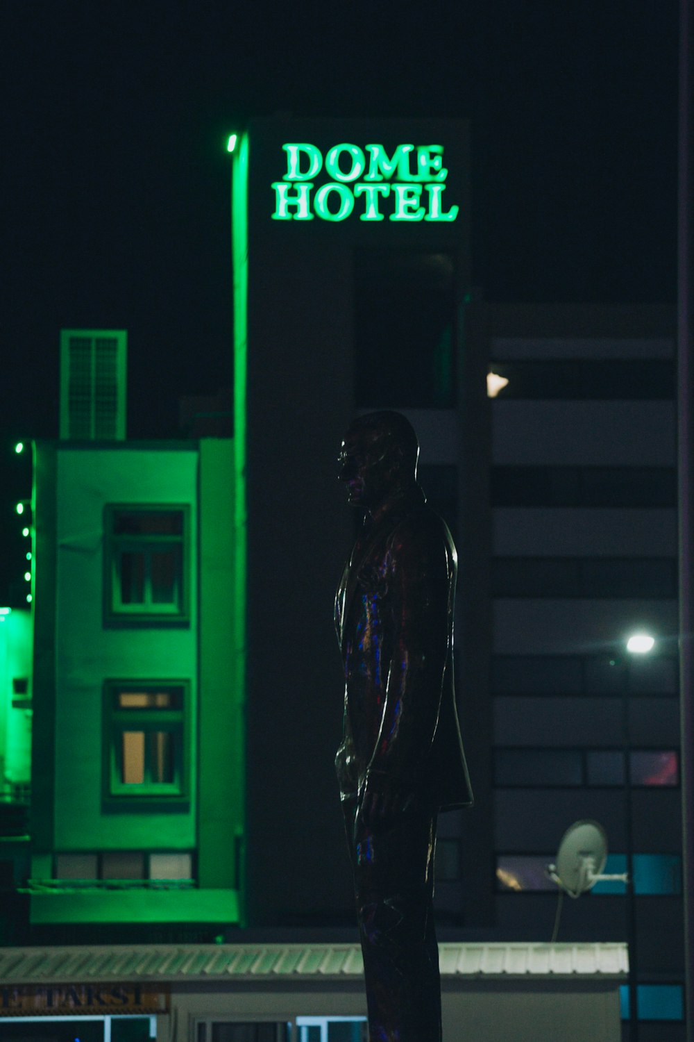 a statue of a person in front of a neon sign