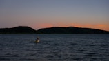 A private couple enjoying a boat ride at sunset with orange and blue skies reflecting on the water